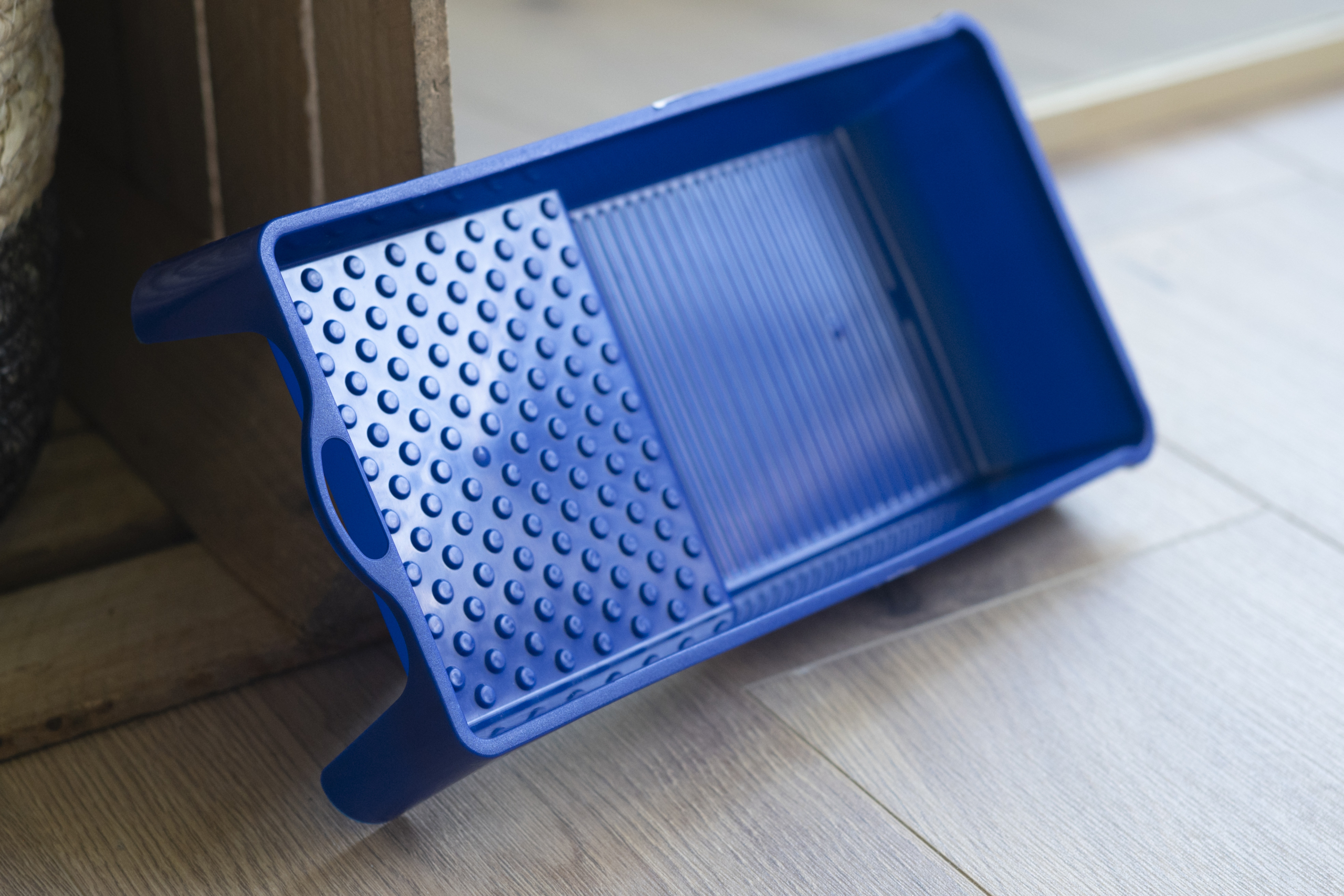 Eine blaue Farbwanne wird an eine Kiste angelehnt.