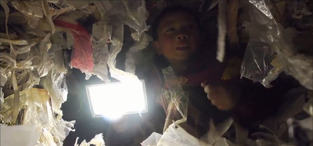 Ein kleiner Junge sitzt in einer Höhle aus Plastikmüll.