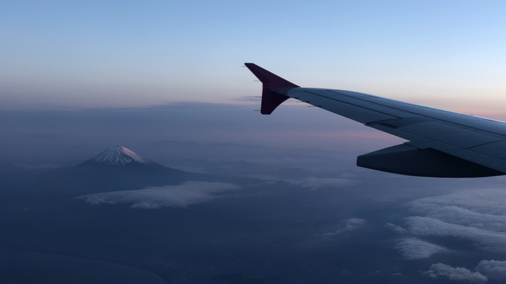 Blick aus einem fliegenden Flugzeug auf den linken Flügel und den Mount Fuji in Japan.