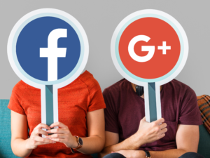 Zwei Menschen halten Schilder nach oben, auf denen die Logos von Facebook und Google+ abgebildet sind.